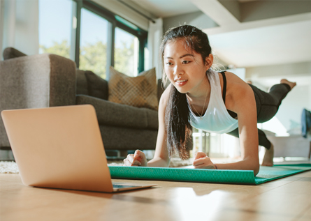 A woman planks in front of her laptop.