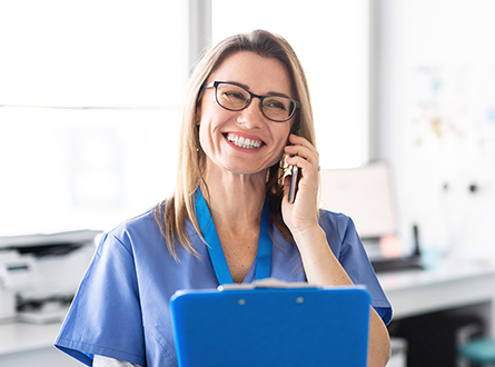A nurse smiles while talking on the phone to a patient.