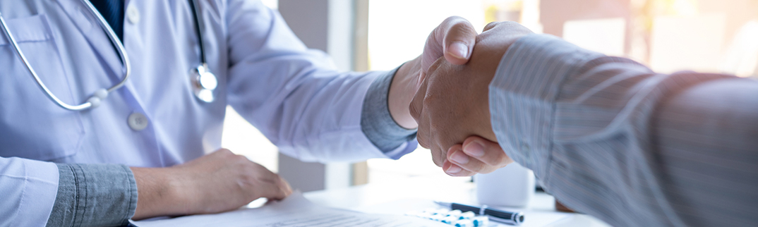 A closeup of a doctor shaking hands with a patient.
