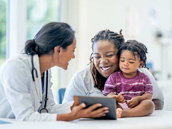 A mother and her daughter smile while looking at some test results with a doctor.