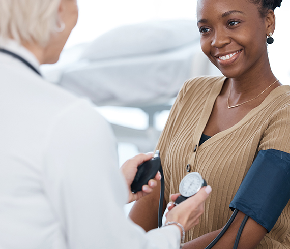A woman smiles while getting her blood pressure taken.