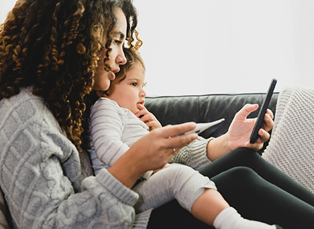 A child and mother sit together facing a phone