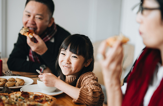 A young girl eats a meal with her family.