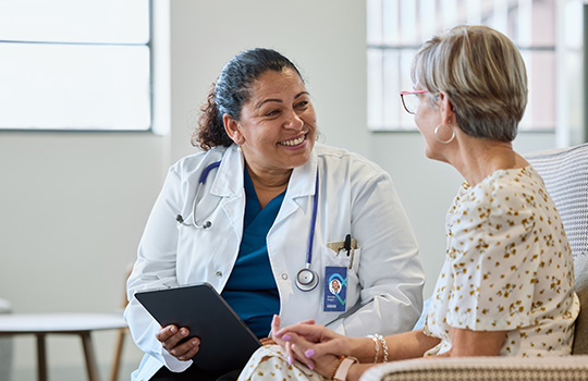 A doctor smiles as they talk to a patient.