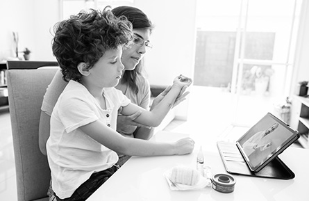 A child and mother sit together facing a tablet