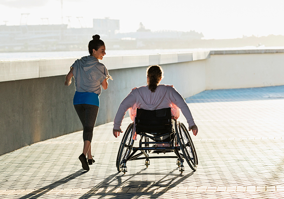 A woman using a wheelchair exercises alongside a woman running.