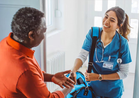 An older adult shakes hands with a health care provider.