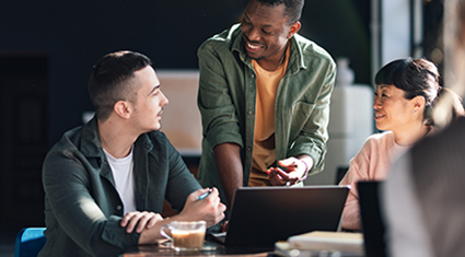Three professional women look at a laptop together