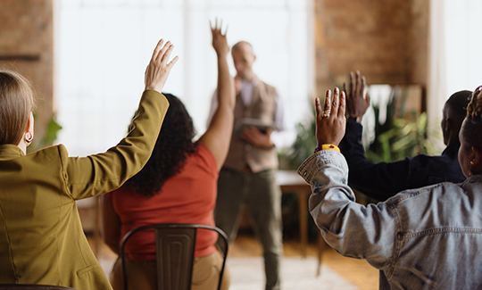 Students raise their hands in a classroom setting.