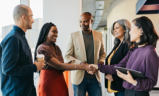 A group of professionals shake hands over a proposal.