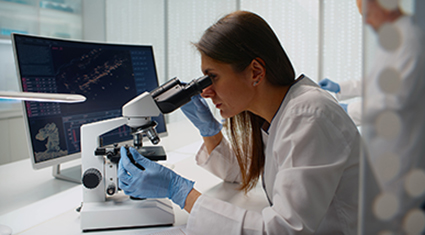 A health care professional looks at a microscope