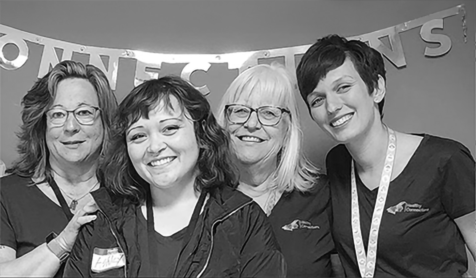 Four nurses stand and smile together. 