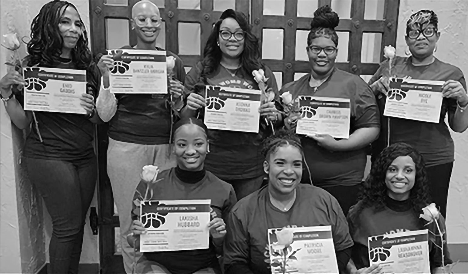 A group of women hold up certificates. 