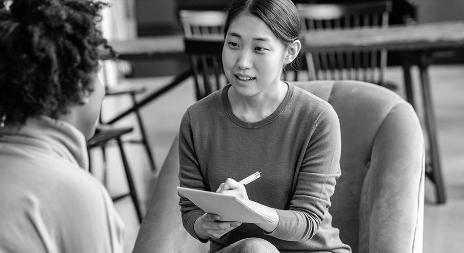 Two young women sit in chairs talking