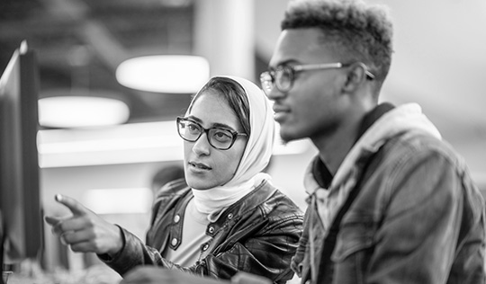 Two students look at a computer screen together