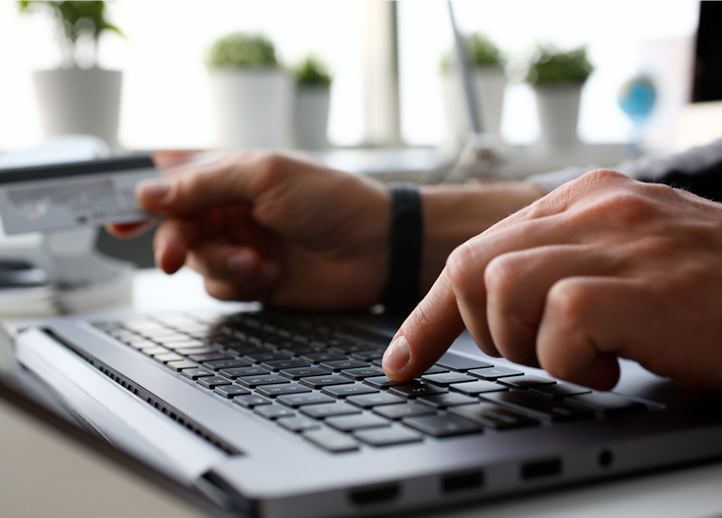 Hands typing on keyboard to report fraud to BCBSM
