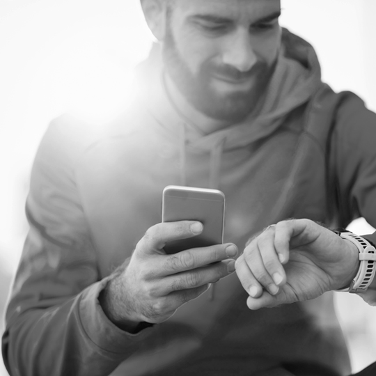A man checks his smart watch and mobile device