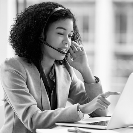 Image of a customer service representative talking with a headset in front of her laptop