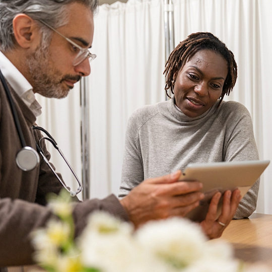 A woman and a health care provider looking at a tablet.