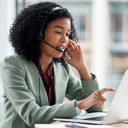 Image of a customer service representative talking with a headset in front of her laptop