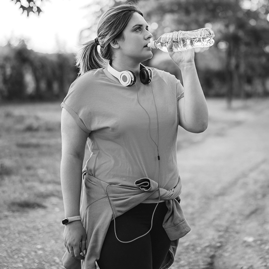 A woman pauses her workout to take a drink of water
