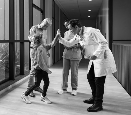 A doctor gives a young patient a high five