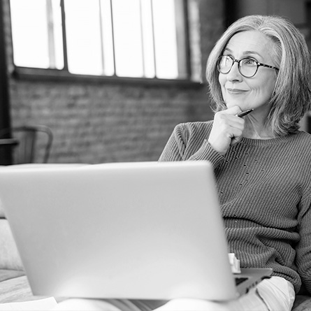 A woman smiles while looking at her computer.