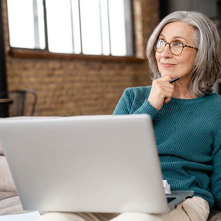 A woman smiles while looking at her computer.
