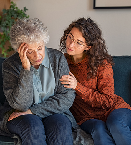 Younger woman sitting with her arm around an older woman
