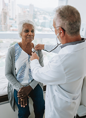 A senior woman waits for her doctor to take her heartbeat.