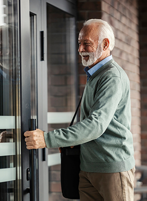 An older man opens a door.