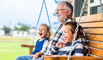 A grandfather on a porch swing with his grandchildren
