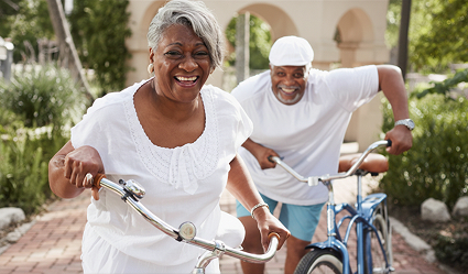 Happy woman and man pushing bicycles.