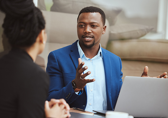 A man in front of a laptop explaining something to a woman