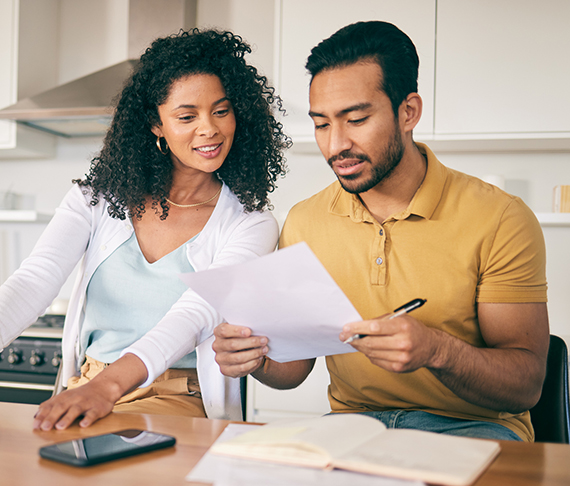 Happy couple sitting at a table looking at documents together.
