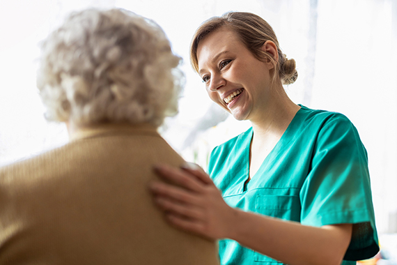 A caregiver embraces her aging loved one.