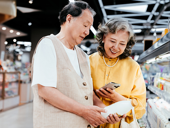 A couple looks at milk together while shopping.