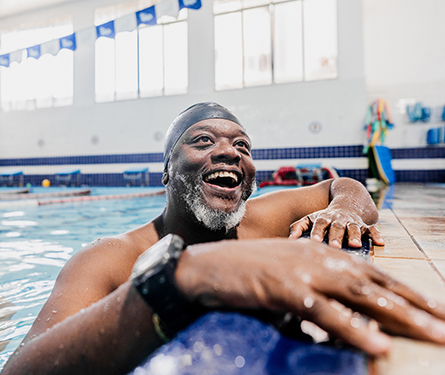 A man resting at the edge of a swimming pool after swimming