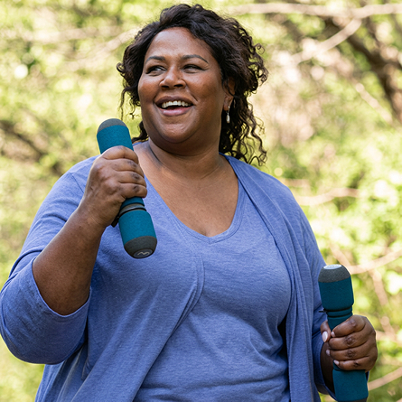 A senior woman lifts weights while working out.