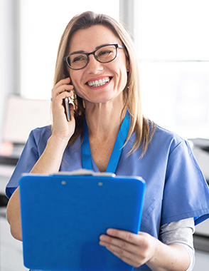 A nurse takes a phone call while holding a clipboard.