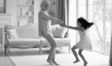 A woman and a child dance around a living room.