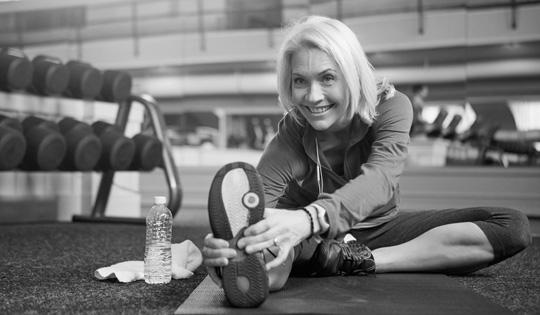 An older woman stretches during a fitness class.