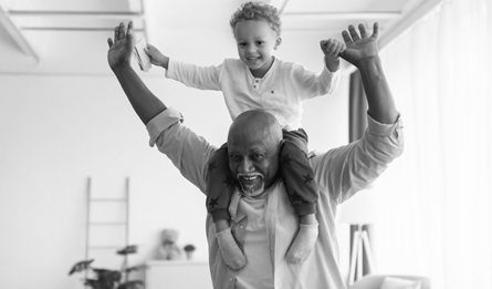 An older man carries a young child on his shoulders.