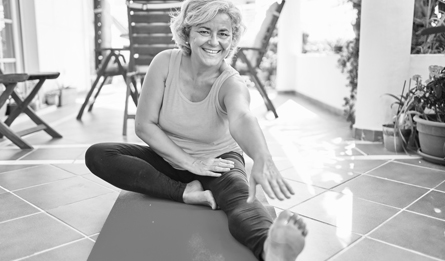 A senior women stretches on a yoga mat. 