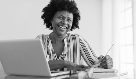 A woman takes notes next to her laptop.