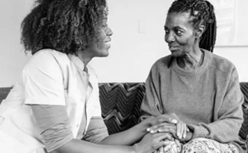 A daughter and mother hold hands while talking.