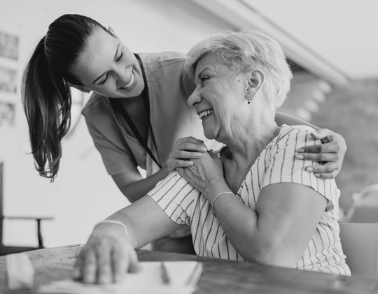 A caregiver embraces her aging loved one.