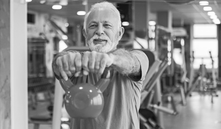 An older man exercises with a kettle ball.