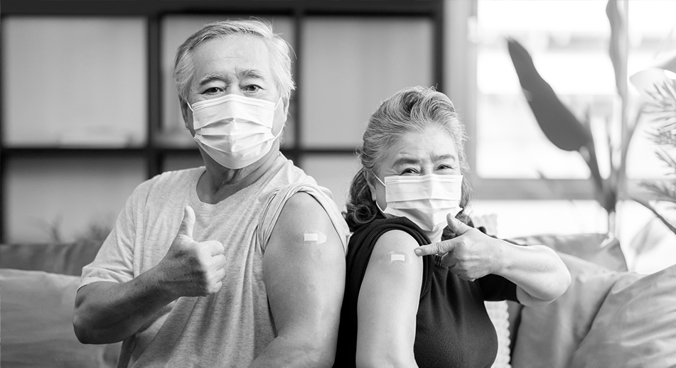 A senior man and woman with small bandages on their arms after getting flu and pneumonia shots.