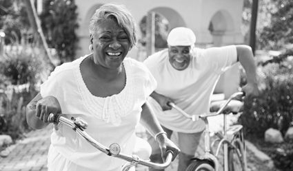 Happy woman and man pushing bicycles.